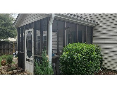 A screened porch with clean gray framing and new mesh screens. The siding of the house has been cleaned.