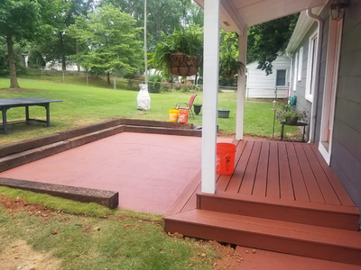 A small red porch extended into a concrete area painted the same color, with wooden retaining walls